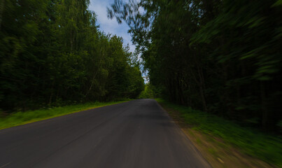 Fototapeta premium The effect of speed on the road and blurred objects. View of the road on a sunny summer day.