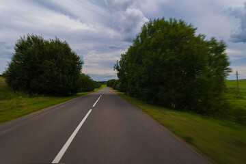 Fototapeta premium The effect of speed on the road and blurred objects. View of the road on a sunny summer day.