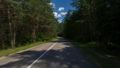 The effect of speed on the road and blurred objects. View of the road on a sunny summer day.