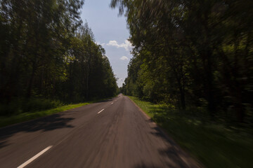 The effect of speed on the road and blurred objects. View of the road on a sunny summer day.