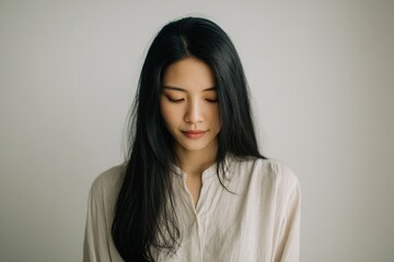 Obraz premium Calm Portrait of Young Asian Woman with Long Hair in Minimalist Setting