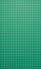 Vertical green cutting mat surface texture with a regular white grid pattern. A measurement and craft background for design, architecture, engineering, or hobby concepts.