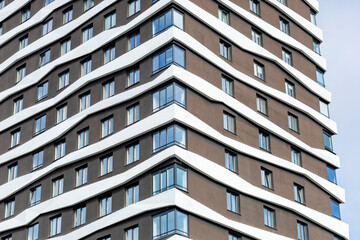 The building's façade features a contemporary design with wavy white elements contrasting with the dark background. Large windows create a feeling of light and space.