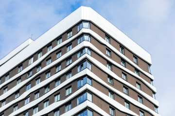 A modern building with a wave-shaped façade, white accents, and large windows. The dynamic design creates a sense of movement and harmony with nature.