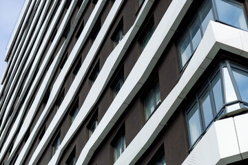 Obraz premium The building's façade features a contemporary design using aluminum composite panels and glazing. The white panels create a dynamic rhythm, while the windows add lightness and transparency.