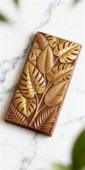 Milk chocolate bar with intricate rainforest leaf patterns, isolated on white marble background