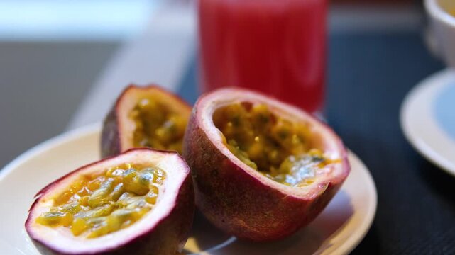 Ripe passion fruits with passion fruit seeds and passionfruit leaves slowly move in the frame on a gray stone table. Nice exotic fruit background for your projects. Macro video shooting. 4k