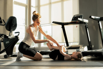 Young mother woman and daughter family doing a hip stretch exercise in fitness gym, promoting strength flexibility, healthy lifestyle guidance wellness.