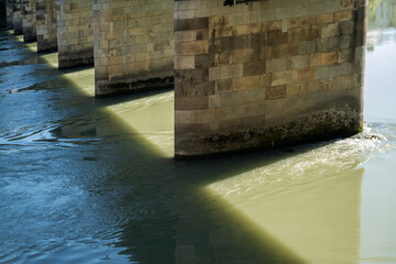 Passau, Bavaria, Germany: sunlight and 
shadows of a bridge on pillars crossing the  fast flowing...