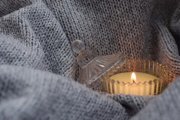 Cozy atmosphere with an aromatic candle on a knitted background.