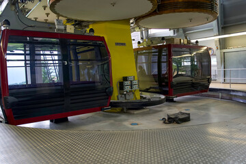 Red gondola lift cabins at a mountain station with modern machinery and scenic views in the background