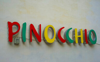 Colorful sign reading Pinocchio in vibrant letters against a textured wall creating a playful atmosphere