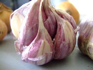 Close-up of fresh purple garlic cloves in natural light, highlighting their texture, color and organic freshness on a kitchen surface