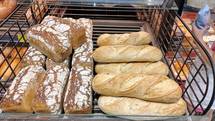Freshly baked loaves of bread in a bakery display basket, including white and whole grain varieties