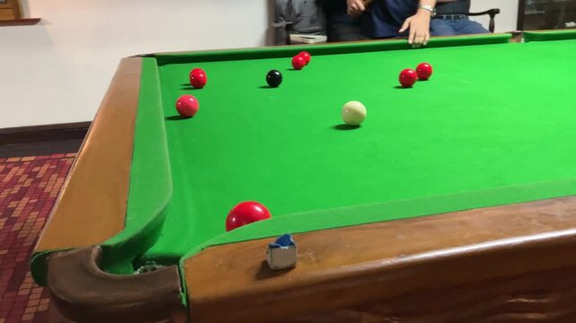 Playing a snooker shot. Indoor games. Indoor activity.