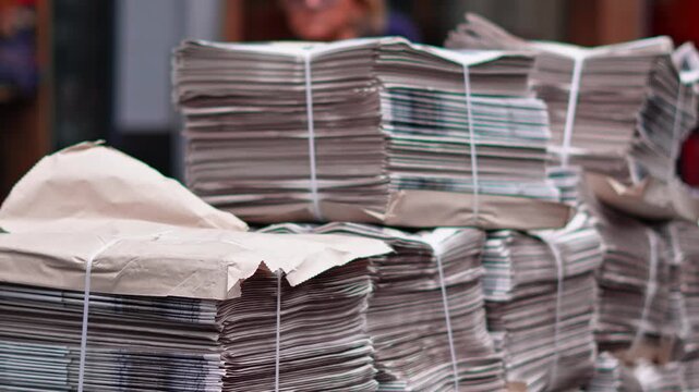 Stacks of newspapers on London sidewalks showing everyday news and urban life.