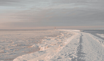 Snowy Path to Lighthouse on Frozen Seashore in Winter