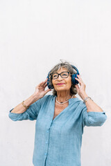 Senior woman enjoying music wearing blue headphones