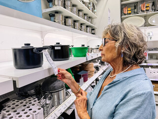 Senior woman shopping for kitchenware comparing price tag