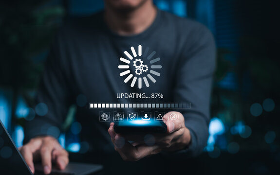 Software Update and System Upgrade Concept. Person holding phone while using laptop with software update progress interface and security, technology maintenance, application upgrades, system security.