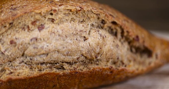 a whole loaf of rye flour bread lies on the table on a cutting board, a small elongated loaf of freshly baked rye bread on an old cutting board for slicing bread