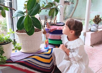 Little girl looking at plants and knitted pots