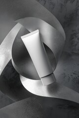 Empty white cosmetic tube mockup against gray background with ribbons