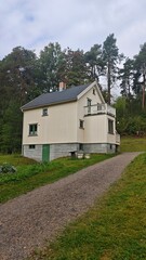 Fototapeta premium Charming cream-colored wooden house with green trim nestled in a quiet forest setting