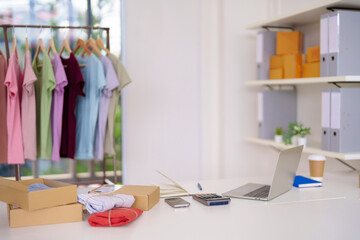 Online clothing store owner managing fashion retail business from home office packaging products for customer orders using technology
