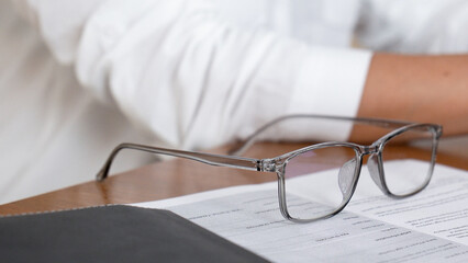 A person wearing glasses reads a book