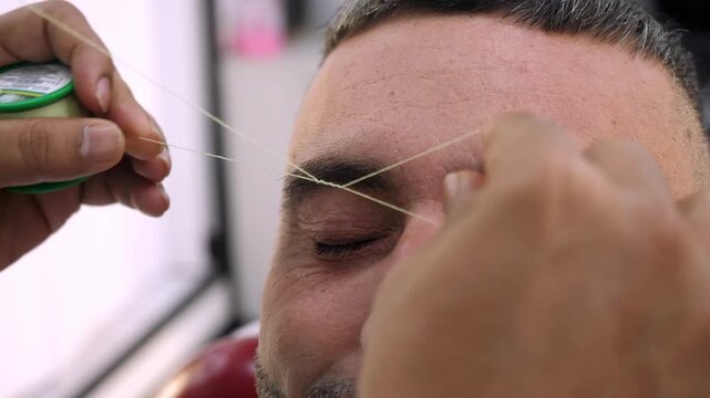 Barber threading eyebrows with Arabic beauty method
