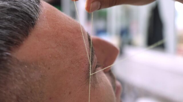 Arabic eyebrow threading by barber for client in Italy

