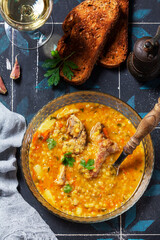 Lentil soup with pork and vegetables, served with white wine and croutons.