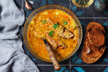 Lentil soup with pork and vegetables, served with white wine and croutons.