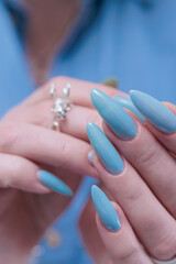 Woman's beautiful hand with long nails and light baby blue manicure