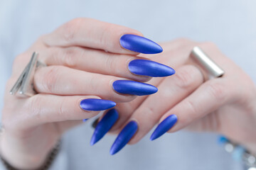 Fototapeta premium Woman's beautiful hand with long nails and blue nail polish