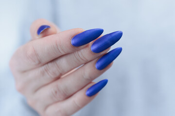 Woman's beautiful hand with long nails and bright blue manicure 