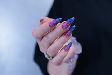 Female hand with long nails and blue and purple thermo french nail polish
