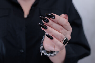 Female hands with long nails and black nail polish