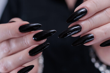 Female hands with long nails and black nail polish