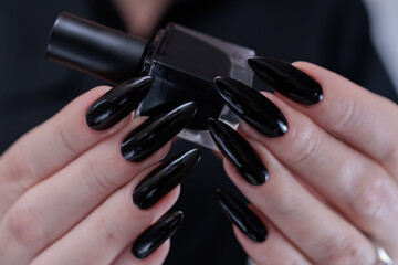 Female hands with long nails and black nail polish