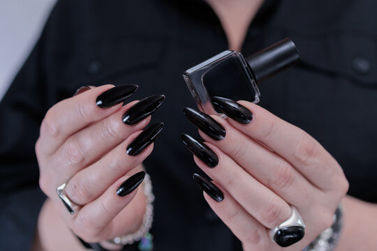 Female hands with long nails and black nail polish