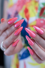 beautiful female hands with long nails and bright neon pink red nail polish