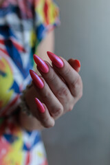 beautiful female hands with long nails and bright neon pink red nail polish