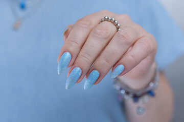 Woman's beautiful hand with long nails and light baby blue manicure