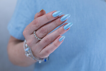 Woman's beautiful hand with long nails and light baby blue manicure	