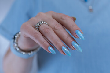 Woman's beautiful hand with long nails and light baby blue manicure	