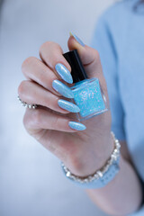 Fototapeta premium Female hand with long nails and bright light blue and silver manicure 