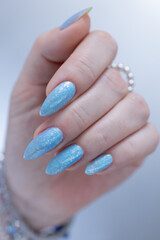 Woman's beautiful hand with long nails and light baby blue manicure	