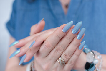 Woman's beautiful hand with long nails and light baby blue manicure	